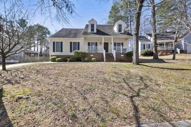 cape cod home with a porch and a front lawn