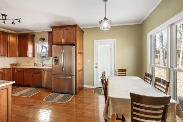 kitchen featuring plenty of natural light, appliances with stainless steel finishes, crown molding, and hardwood / wood-style flooring