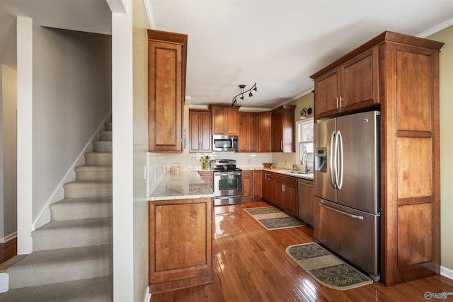 kitchen featuring brown cabinets, a sink, hardwood / wood-style floors, stainless steel appliances, and decorative backsplash