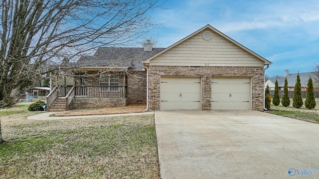 view of front of house featuring brick siding, a chimney, covered porch, an attached garage, and driveway