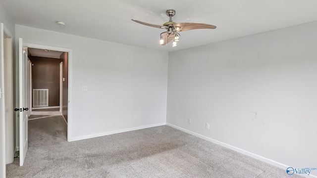 carpeted spare room featuring baseboards, visible vents, and ceiling fan