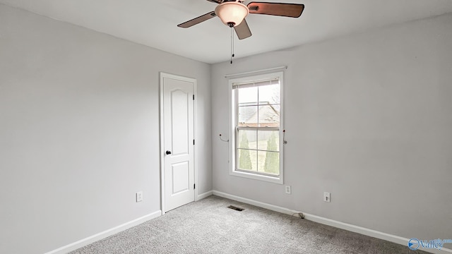 empty room featuring ceiling fan, carpet floors, visible vents, and baseboards