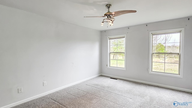 carpeted empty room featuring visible vents, ceiling fan, and baseboards