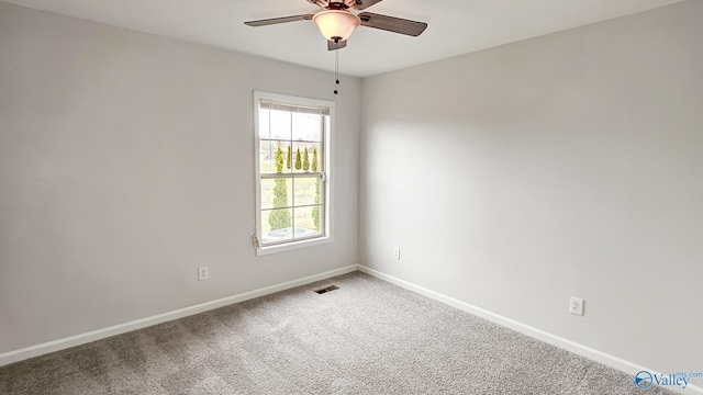 carpeted spare room featuring a ceiling fan, visible vents, and baseboards