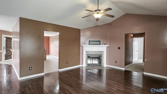 unfurnished living room with lofted ceiling, baseboards, a tiled fireplace, and wood finished floors