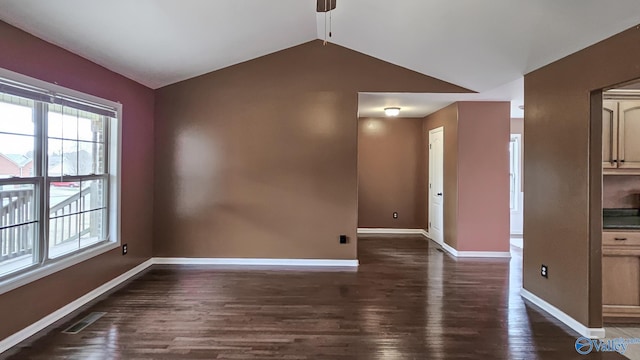 empty room featuring vaulted ceiling, dark wood-style flooring, visible vents, and baseboards