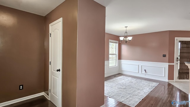 foyer featuring a wainscoted wall, wood finished floors, and an inviting chandelier