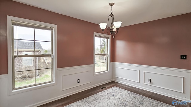 spare room with a chandelier, dark wood-style flooring, and a wainscoted wall