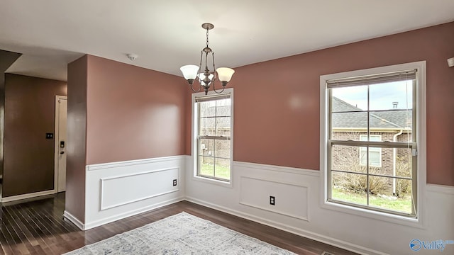 unfurnished dining area featuring a wealth of natural light, dark wood-style flooring, and wainscoting