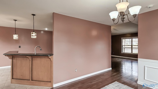 kitchen with light wood-style floors, baseboards, pendant lighting, and a notable chandelier