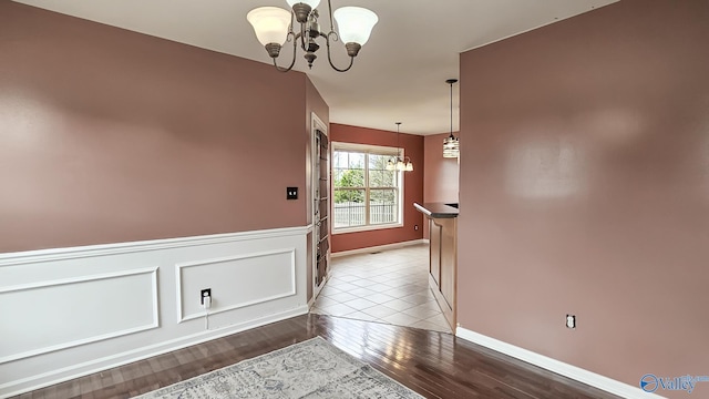 interior space with a wainscoted wall, wood finished floors, and a notable chandelier