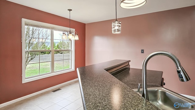 kitchen featuring dark countertops, a sink, a wealth of natural light, and pendant lighting