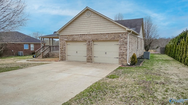 view of home's exterior featuring a garage, concrete driveway, a yard, central AC, and brick siding