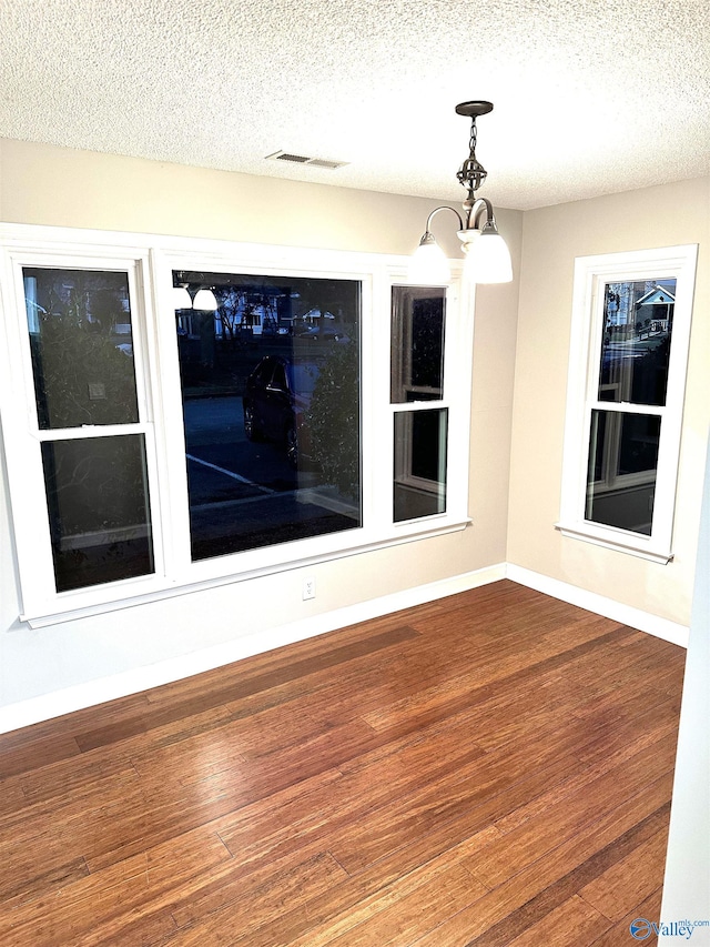 interior space featuring hardwood / wood-style flooring, a textured ceiling, and a chandelier