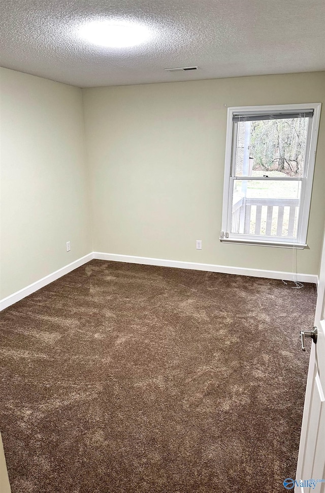 carpeted empty room featuring a textured ceiling