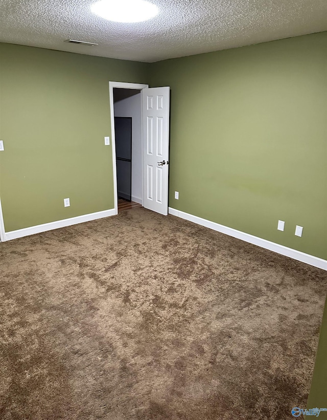 unfurnished room featuring a textured ceiling and carpet floors