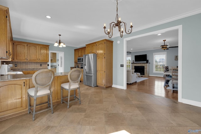 kitchen featuring hanging light fixtures, stainless steel appliances, crown molding, backsplash, and a kitchen bar