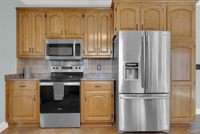 kitchen with decorative backsplash, light tile patterned floors, and stainless steel appliances