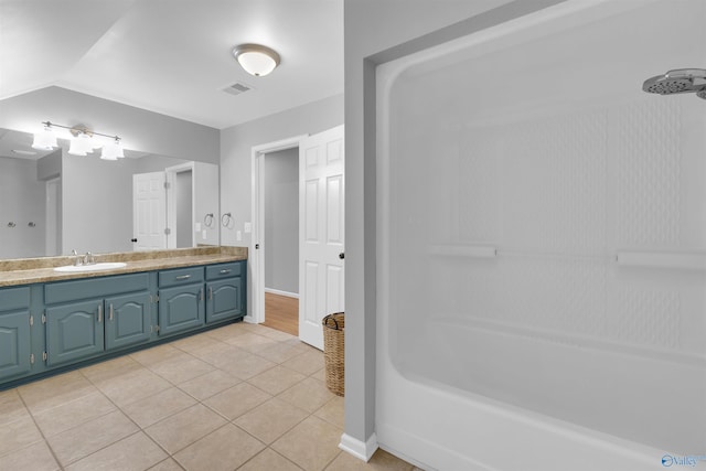 bathroom with a shower, tile patterned flooring, and vanity