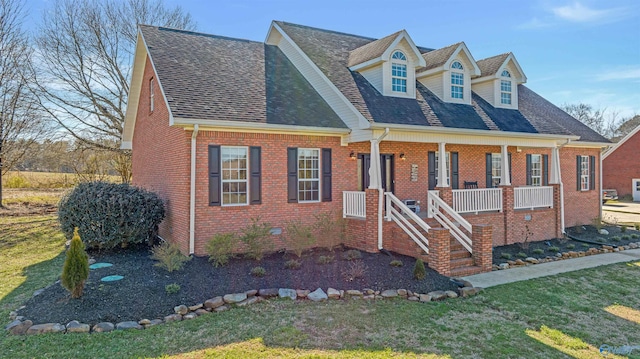 new england style home featuring a front lawn and a porch