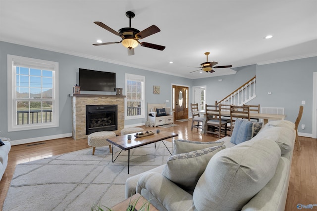 living room with a healthy amount of sunlight, crown molding, light wood-type flooring, and ceiling fan