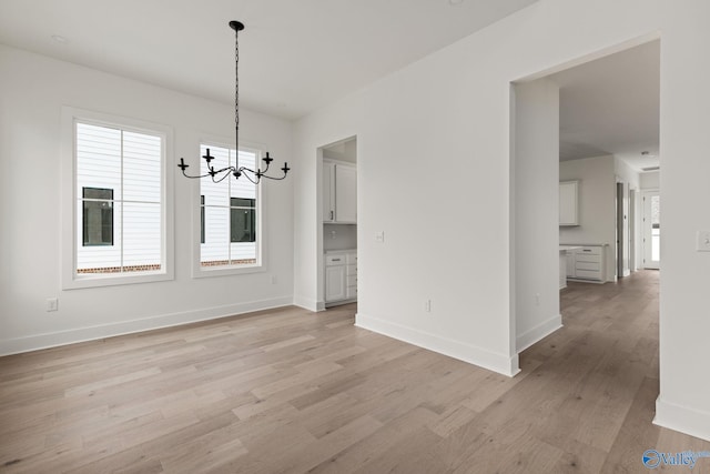 201 Fame Ave, Tuscumbia, AL 35674 - unfurnished dining area with an inviting chandelier, baseboards, and light wood-type flooring