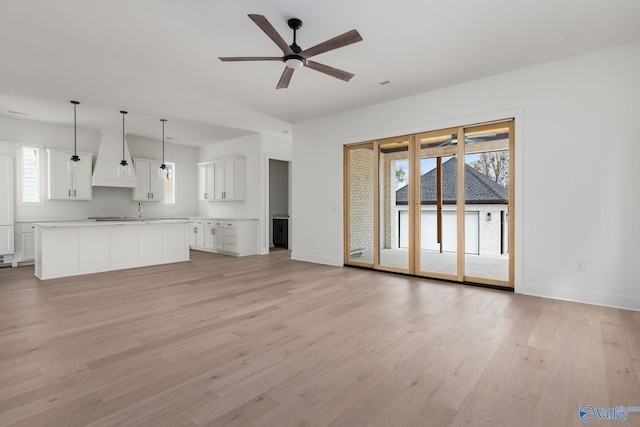 201 Fame Ave, Tuscumbia, AL 35674 - unfurnished living room featuring a ceiling fan, baseboards, a sink, and light wood-style floors