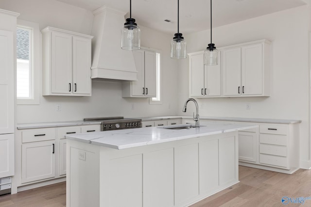 201 Fame Ave, Tuscumbia, AL 35674 - kitchen with white cabinets, an island with sink, a sink, and light wood-type flooring
