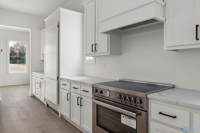 201 Fame Ave, Tuscumbia, AL 35674 - kitchen with wood finished floors, custom exhaust hood, white cabinetry, light stone counters, and stainless steel range