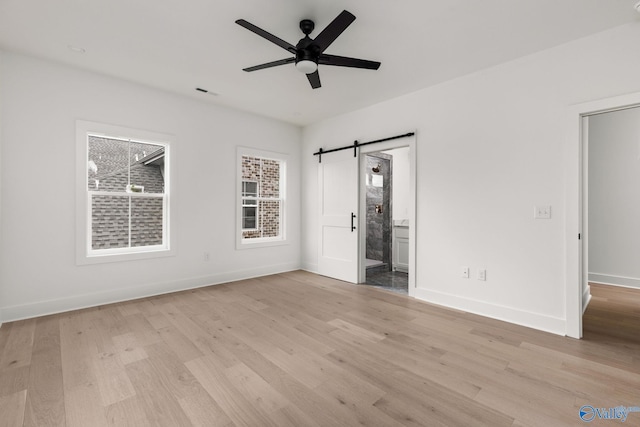 201 Fame Ave, Tuscumbia, AL 35674 - unfurnished bedroom with visible vents, ensuite bathroom, baseboards, a barn door, and light wood finished floors