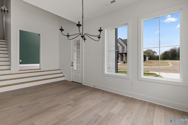 201 Fame Ave, Tuscumbia, AL 35674 - unfurnished dining area featuring visible vents, an inviting chandelier, baseboards, stairway, and light wood finished floors