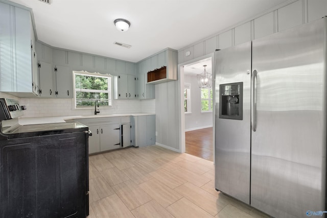 101 Arcade St, Gadsden, AL 35901 - kitchen with stainless steel fridge, electric range, a chandelier, light countertops, and tasteful backsplash