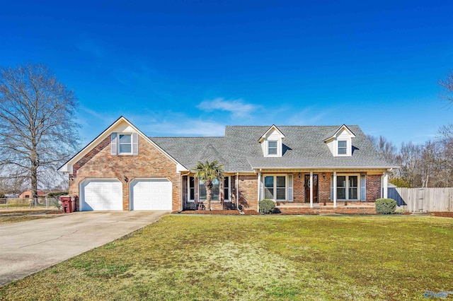 new england style home with driveway, an attached garage, fence, a front lawn, and brick siding