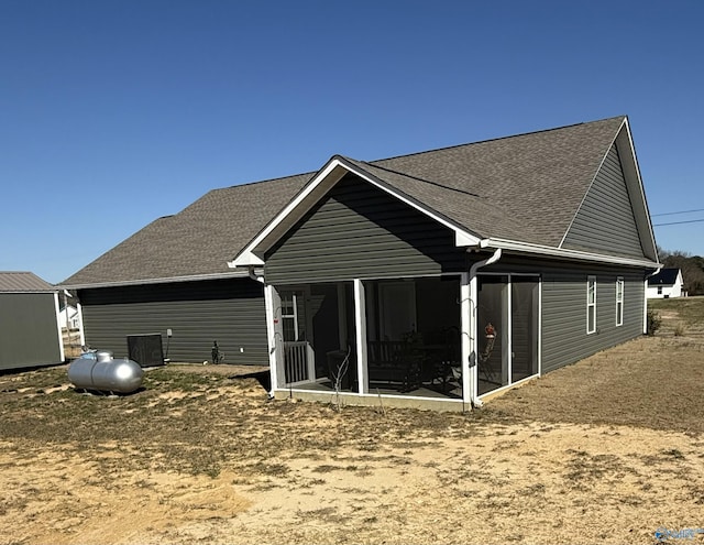 back of property with a sunroom and roof with shingles