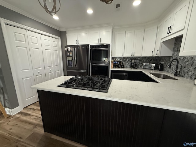 kitchen featuring light stone countertops, white cabinets, a sink, wood finished floors, and black appliances