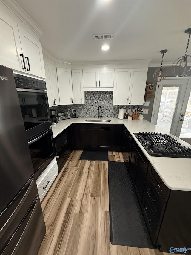 kitchen with black gas stovetop, a sink, visible vents, light countertops, and freestanding refrigerator