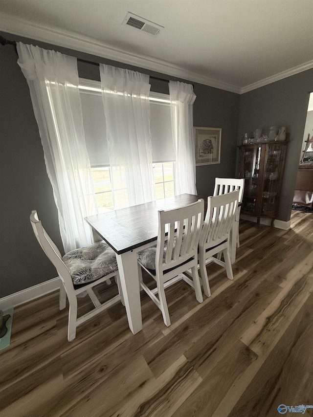 dining area with baseboards, wood finished floors, visible vents, and crown molding