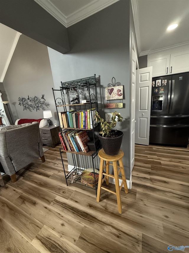 interior space featuring crown molding, black refrigerator with ice dispenser, and wood finished floors