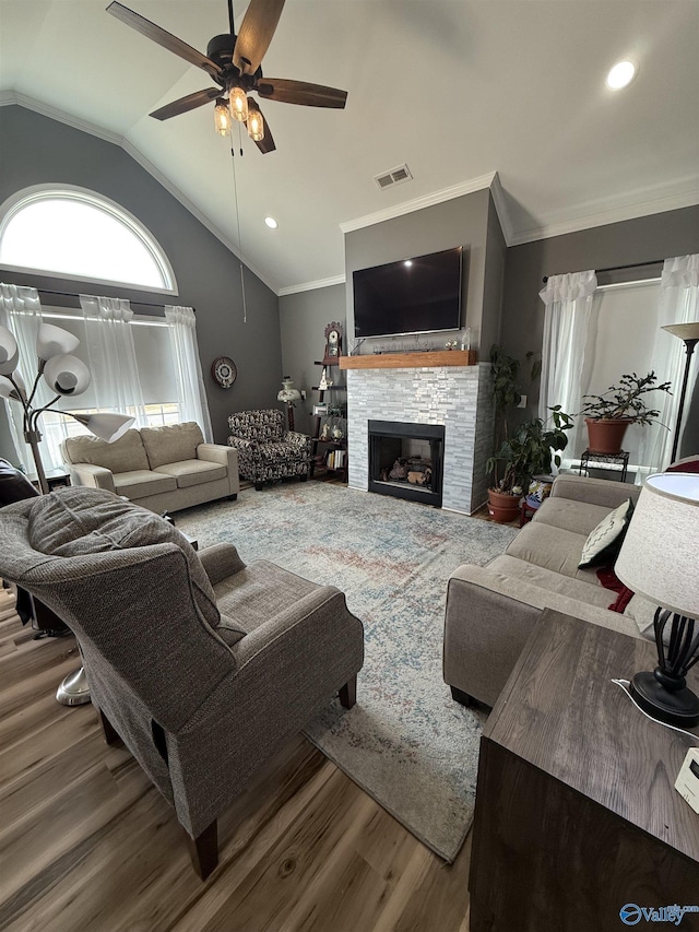 living area featuring lofted ceiling, a fireplace, visible vents, and ornamental molding