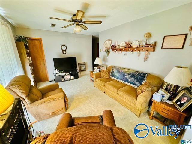 carpeted living room with ceiling fan