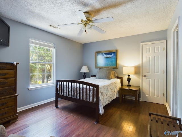 bedroom with dark wood-type flooring, ceiling fan, and a textured ceiling