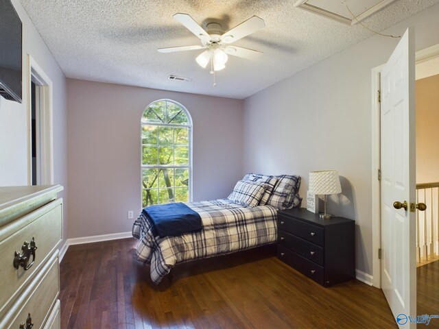 bedroom featuring dark hardwood / wood-style flooring, ceiling fan, and a textured ceiling