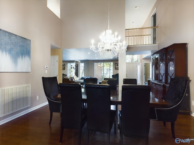 dining space featuring a towering ceiling, dark hardwood / wood-style flooring, and a chandelier