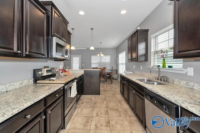 kitchen with sink, light stone counters, light tile patterned floors, pendant lighting, and stainless steel appliances