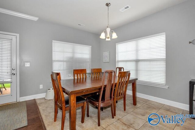 tiled dining space with a healthy amount of sunlight, crown molding, and a chandelier