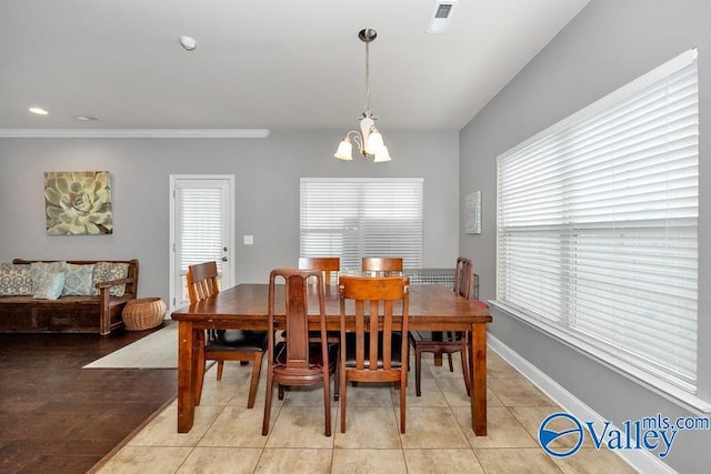 tiled dining space featuring an inviting chandelier and ornamental molding