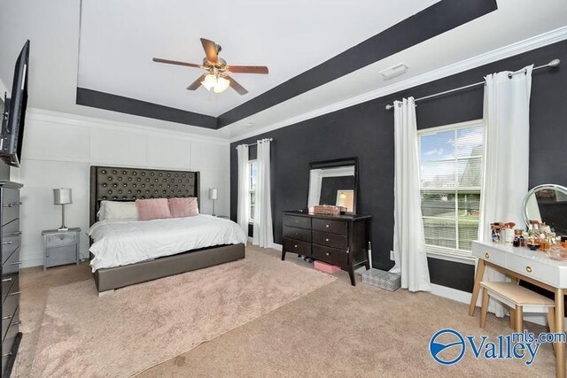 carpeted bedroom with ceiling fan and a tray ceiling