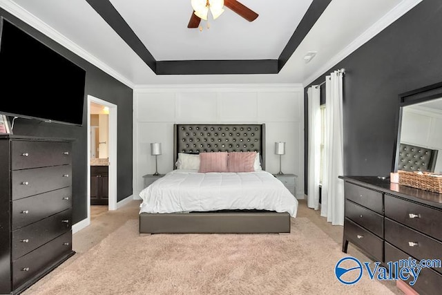 bedroom with ceiling fan, ornamental molding, light carpet, a raised ceiling, and ensuite bathroom