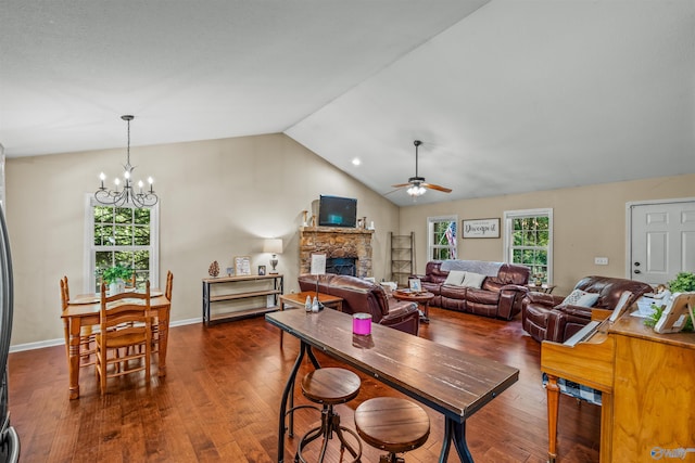 dining room featuring vaulted ceiling, dark wood-type flooring, ceiling fan with notable chandelier, and a fireplace