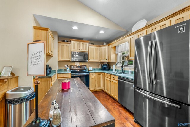 kitchen featuring light brown cabinets, hardwood / wood-style floors, lofted ceiling, stainless steel appliances, and sink